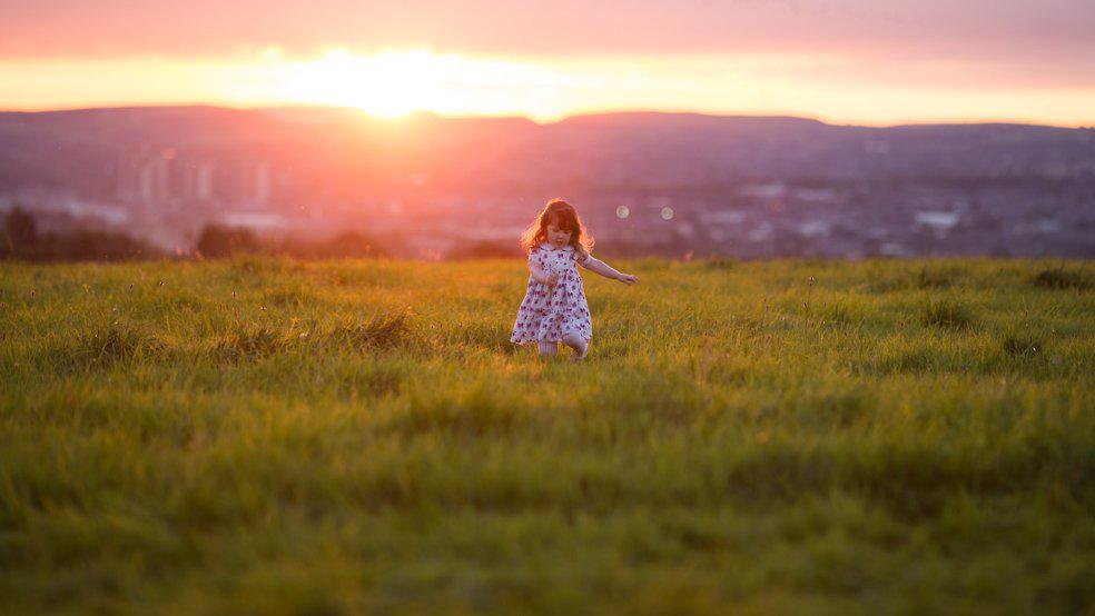 A girl plays in a field at sunset at a Pennine Tipi wedding