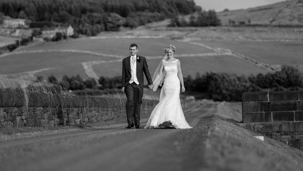 Saddleworth farm barn wedding, walking along the reservoir path - the bride in a stunning fishtail dress